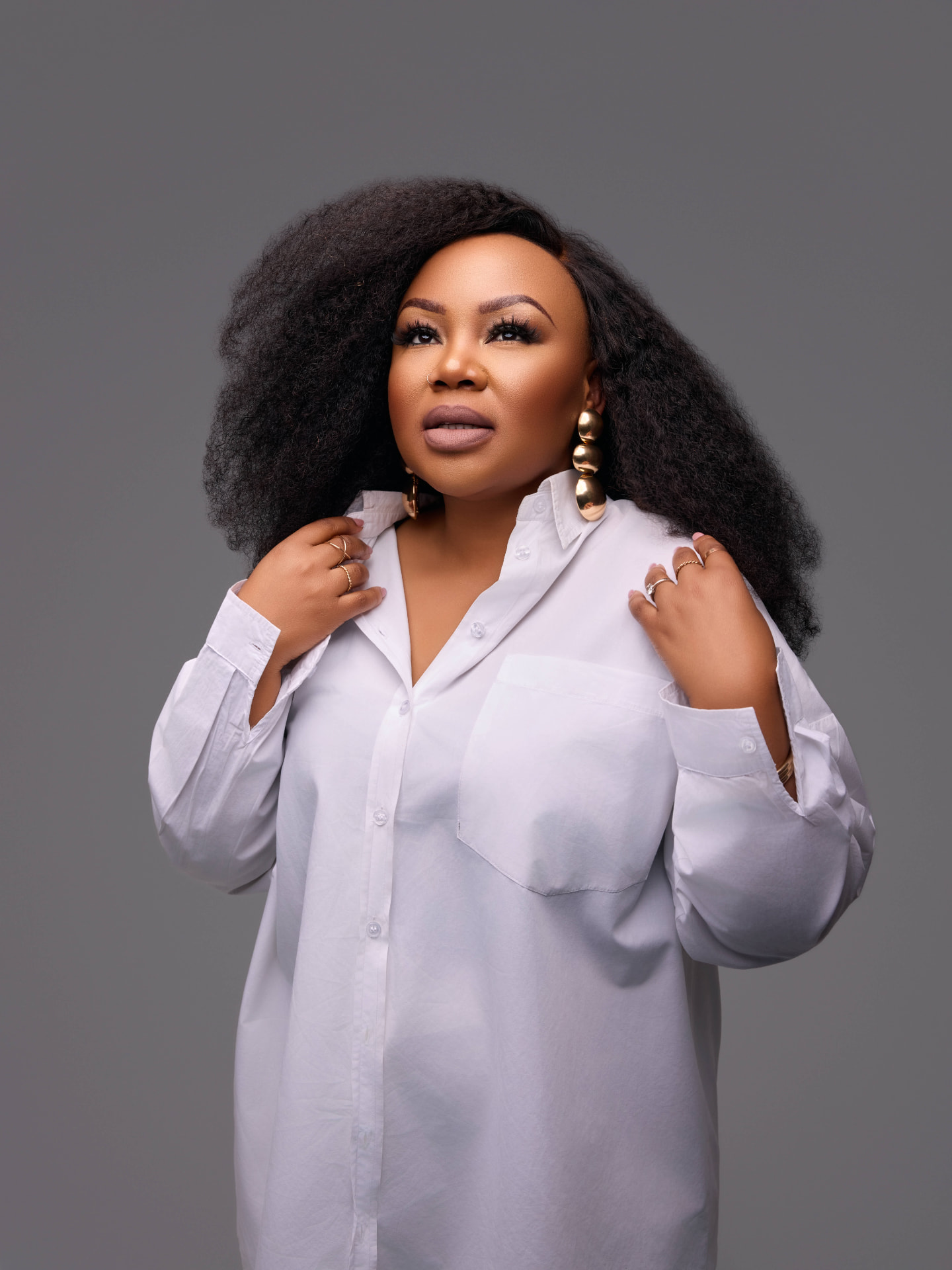 Lebo Thabethe in a crisp white shirt with gold statement earrings